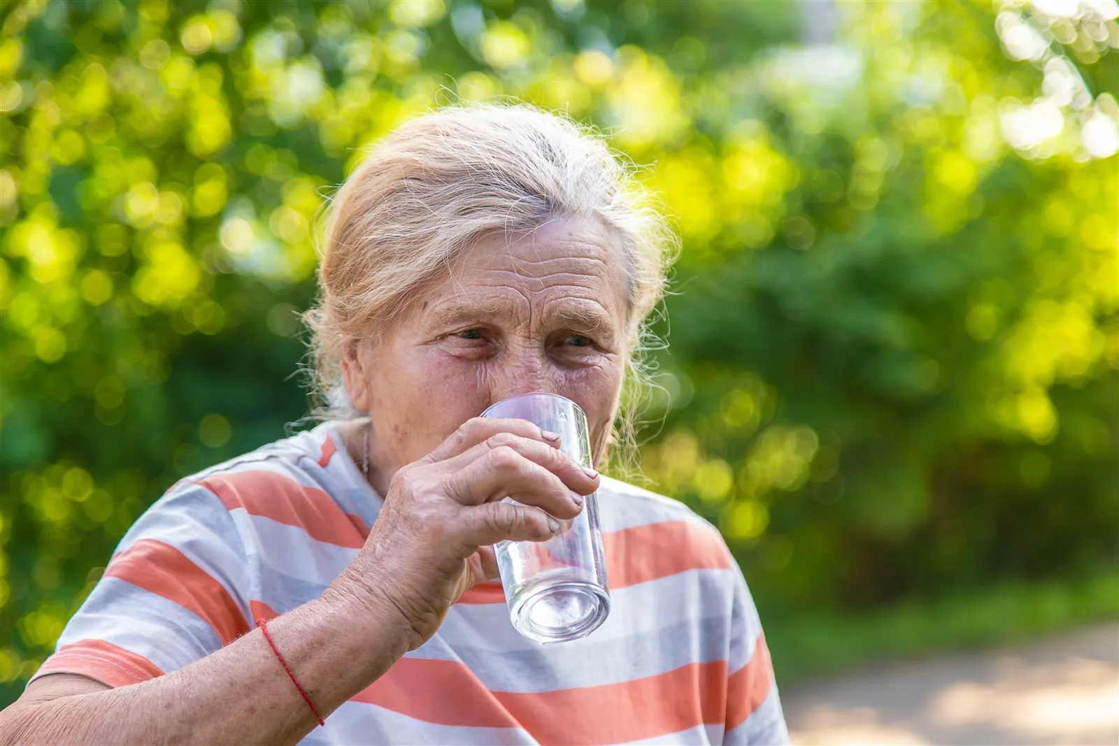 Keeping Older People Safe in Hot Weather Older woman drinking a glass of water outdoors in summer
