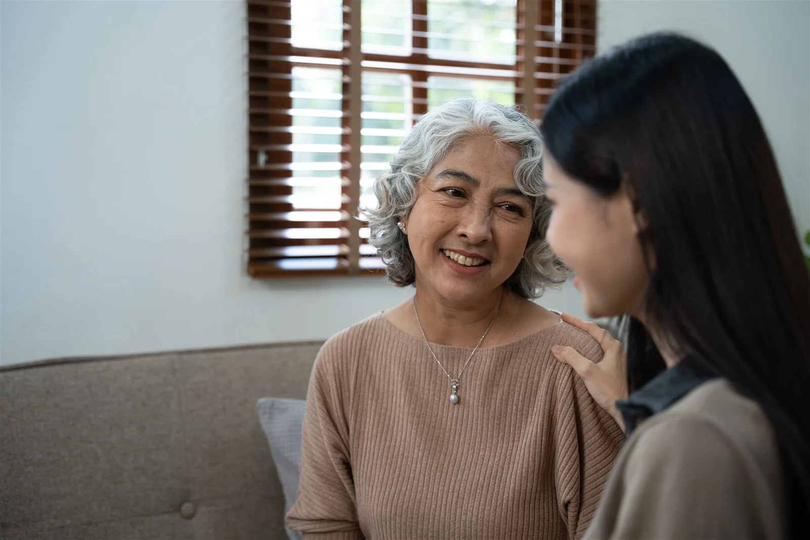 Older woman laughing with a younger female companion at home